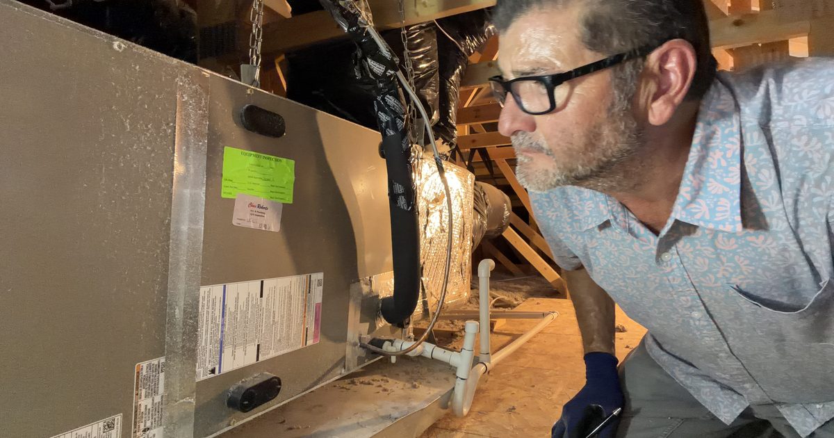 Kelly Lopez of Leading Edge Plus Inspections examining an attic-mounted HVAC air handler during an East Valley, AZ home inspection