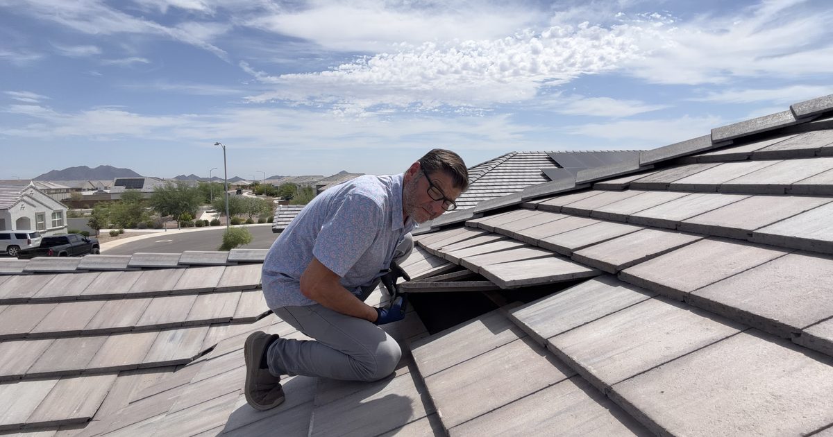 Kelly Lopez on a concrete tile roof in Gilbert, AZ, lifting a tile to inspect the underlayment after monsoon storms