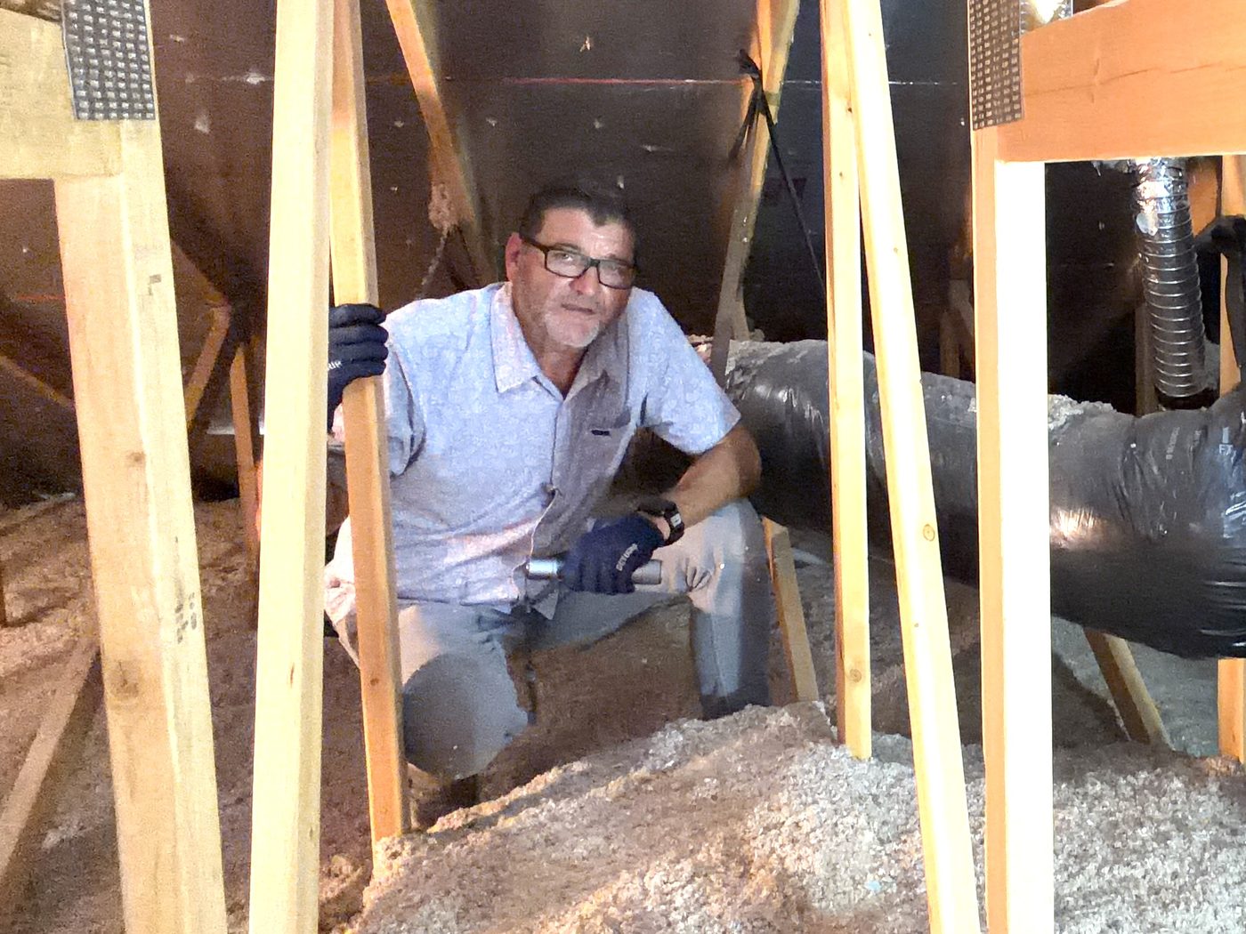 Kelly Lopez inspecting roof framing, ductwork and insulation inside the attic of a newly built Gilbert, AZ home